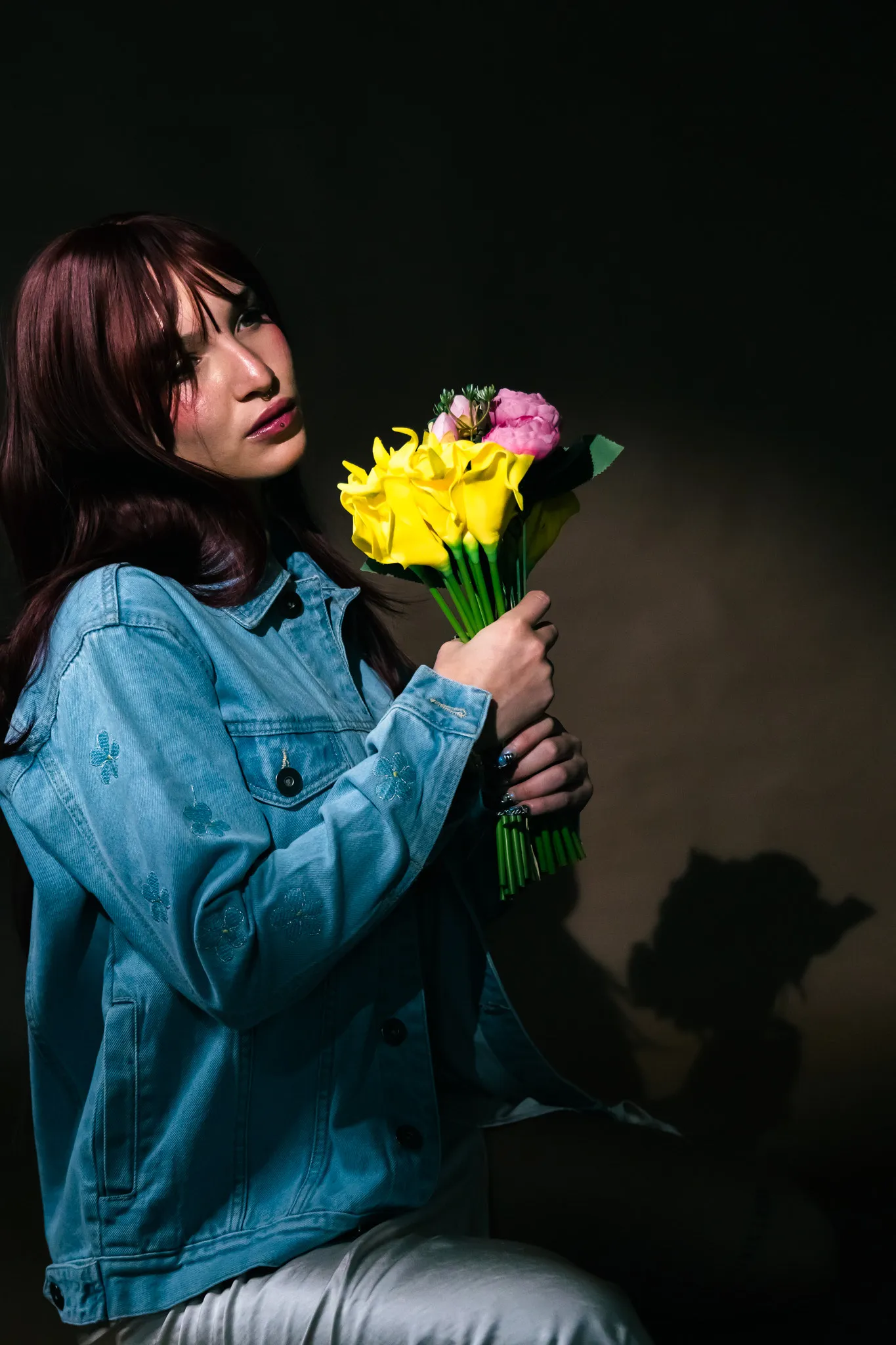 Model in an embroidered denim jacket holding flowers